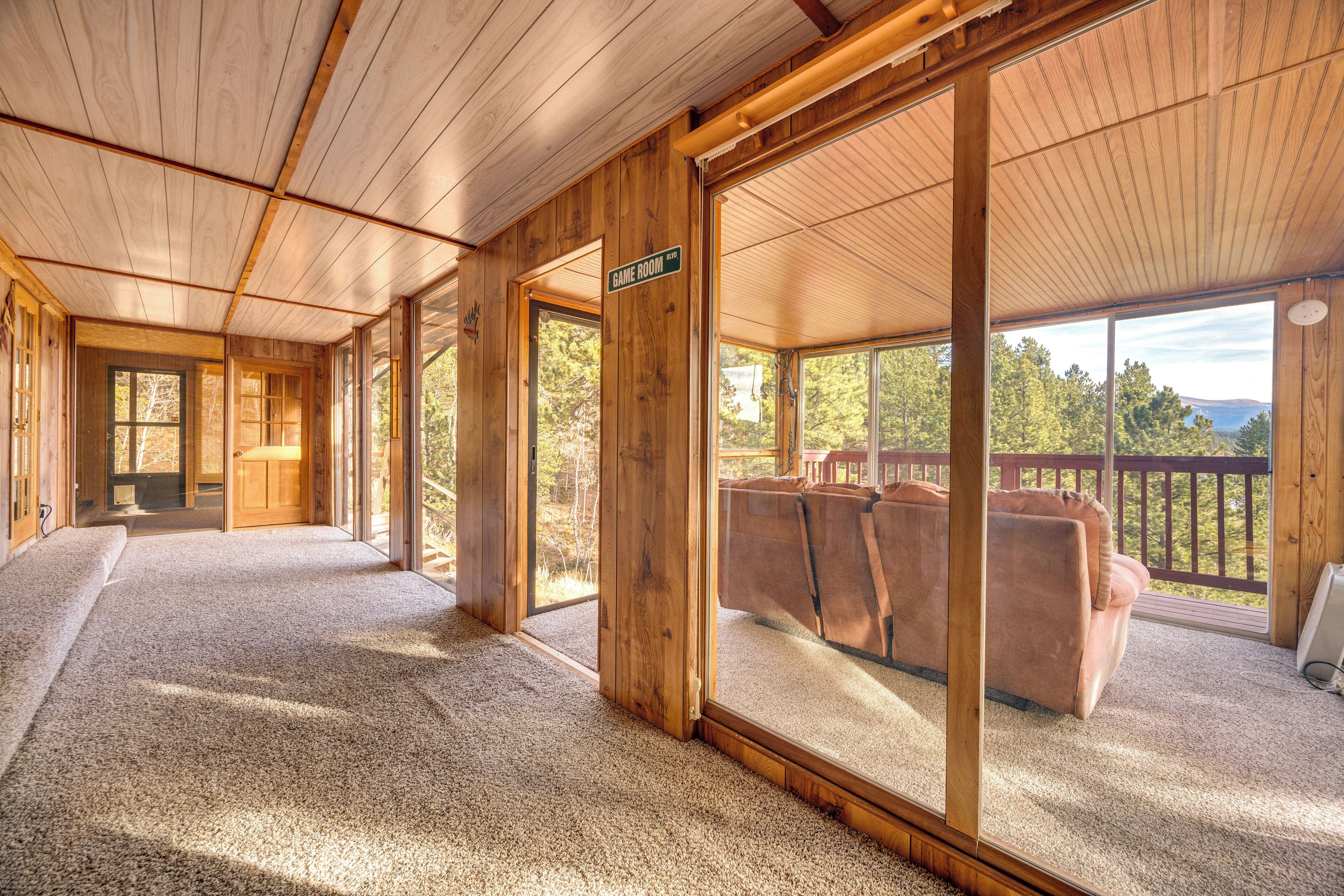 Un intérieur en bois avec un sol recouvert de moquette, une enseigne indiquant la présence d’une salle de jeux et une vue sur l’extérieur.