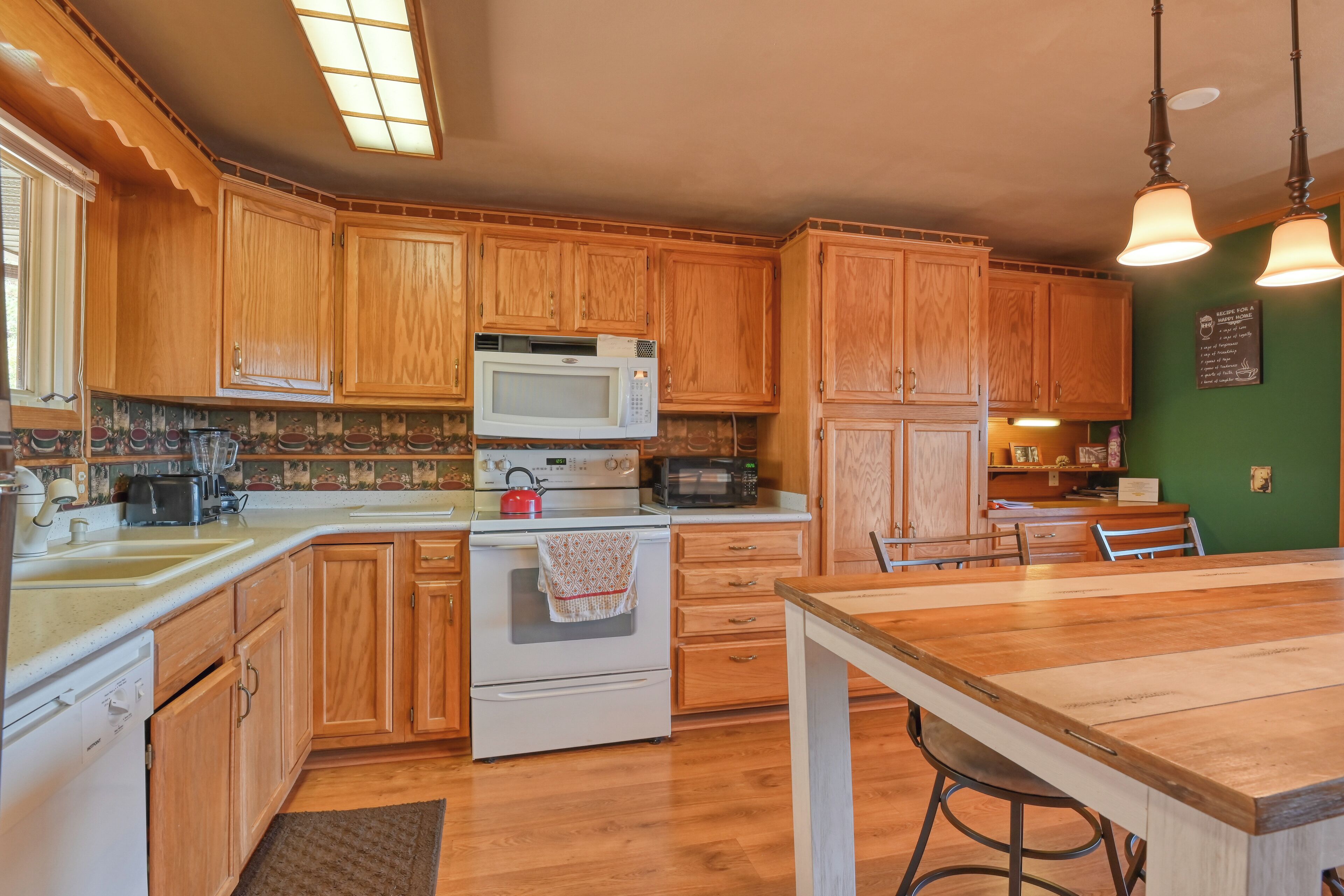 A kitchen with wooden cabinets, a white stove, a microwave, and a dining area with a wooden table and chairs.