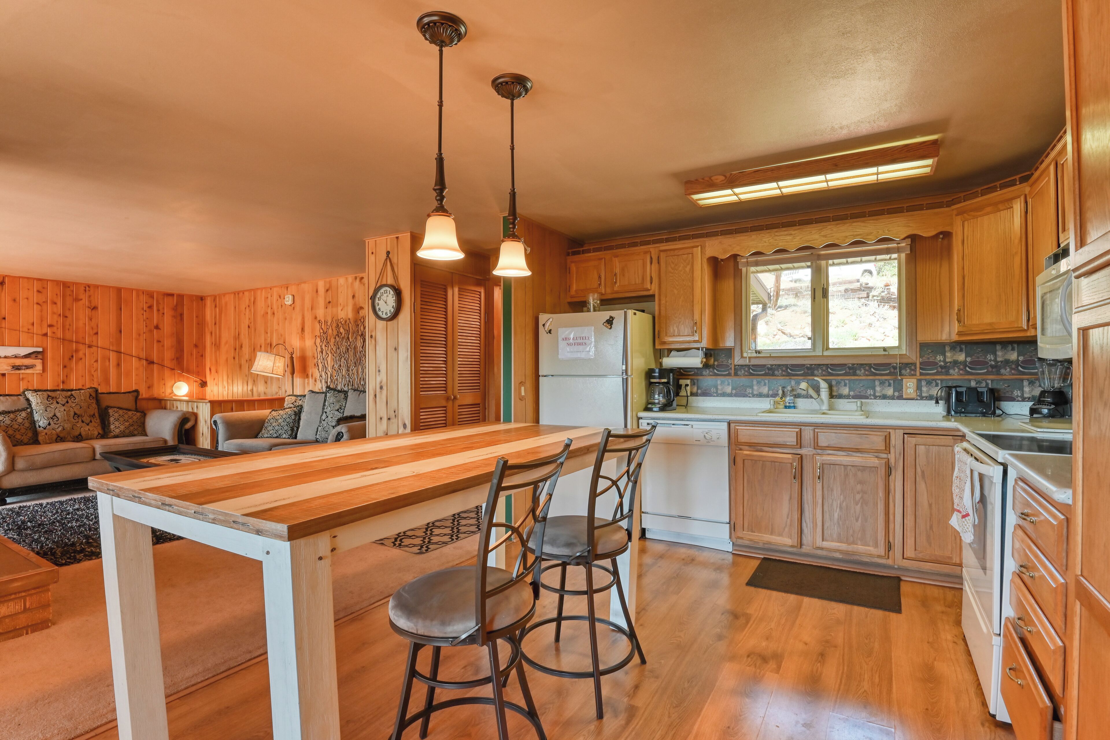 A kitchen with wooden cabinets, a refrigerator, a stove, and a dining area with a table and chairs.