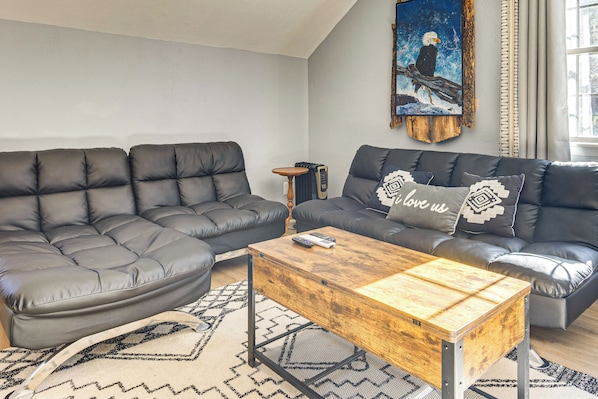 A modern living room with a sectional sofa, a wooden coffee table, and a painting of an eagle. - Fish, Hike & Explore: Mtn-view Lake George Studio (Florissant)
