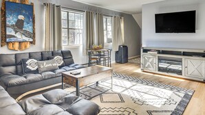 Una sala de estar moderna con un sofá modular, una mesa de centro, un televisor y una chimenea.