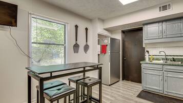 A modern kitchen with a bar area, stainless steel appliances, and a window with blinds.