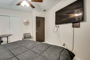 A bedroom with a bed, a chair, a desk, a TV mounted on the wall, and a ceiling fan. - Easy Hwy Access to Atl: Work-ready Riverdale Home (Riverdale)