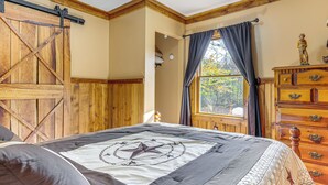 Quarto com cama grande, guarda-roupa de madeira e janela com cortinas.