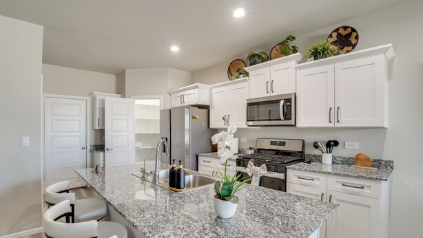 A modern kitchen with white cabinets, granite countertops, and stainless steel appliances.