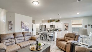 A modern living room with leather sofas, a coffee table, and a kitchen in the background.