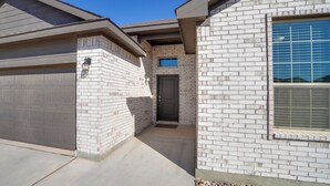 A residential building with a garage, a front door, and a window with blinds.