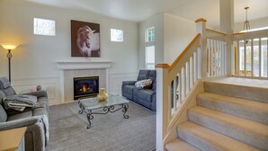 Una sala de estar con chimenea, una escalera y un sofá.