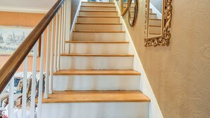 Una escalera con escalones de madera y barandillas blancas, que conduce a una plataforma con vistas al exterior.