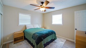 A bedroom with a bed, a ceiling fan, a nightstand, and two windows. - 1 Mi to Enmu: Portales Family Home w/ Yard! (Portales)