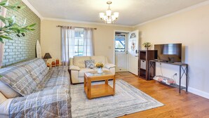 A living room with a sofa, coffee table, TV stand, and a brick accent wall. - Quiet Home Base in the Heart of Boardman! (Boardman)