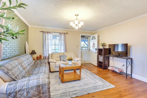 A living room with a sofa, coffee table, TV stand, and a brick accent wall. - Quiet Home Base in the Heart of Boardman! (Boardman)