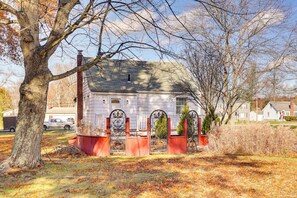 A white house with a red brick chimney, a metal gate, and a large tree in the foreground. - Quiet Home Base in the Heart of Boardman! (Boardman)