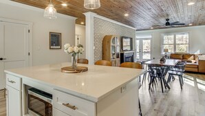 Une cuisine spacieuse dotée d’un grand îlot central, d’un plafond en bois et de luminaires suspendus.