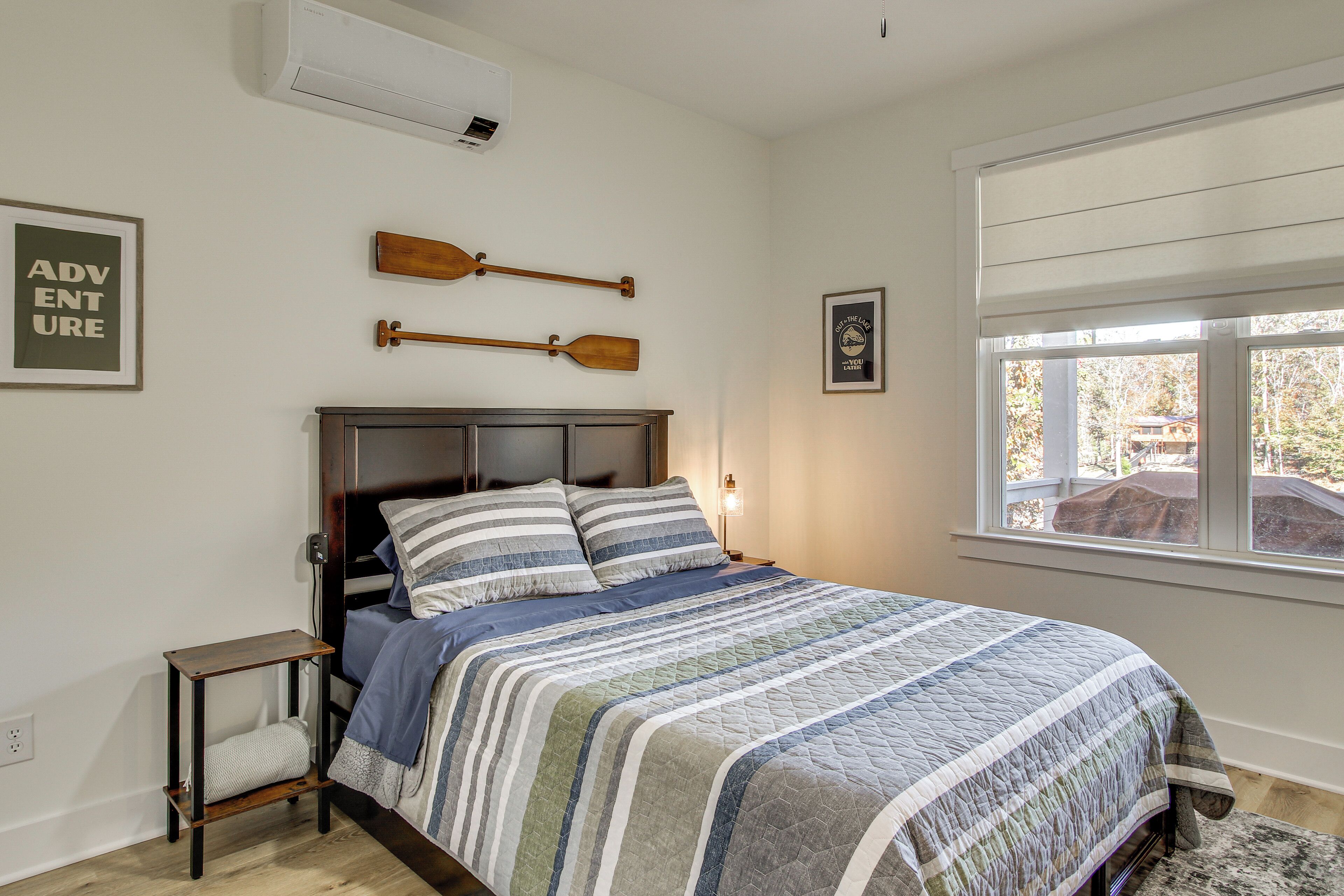 Ein Schlafzimmer mit einem Bett, einem kleinen Nachttisch, zwei Holzschlägern an der Wand und einem Fenster mit Blick.