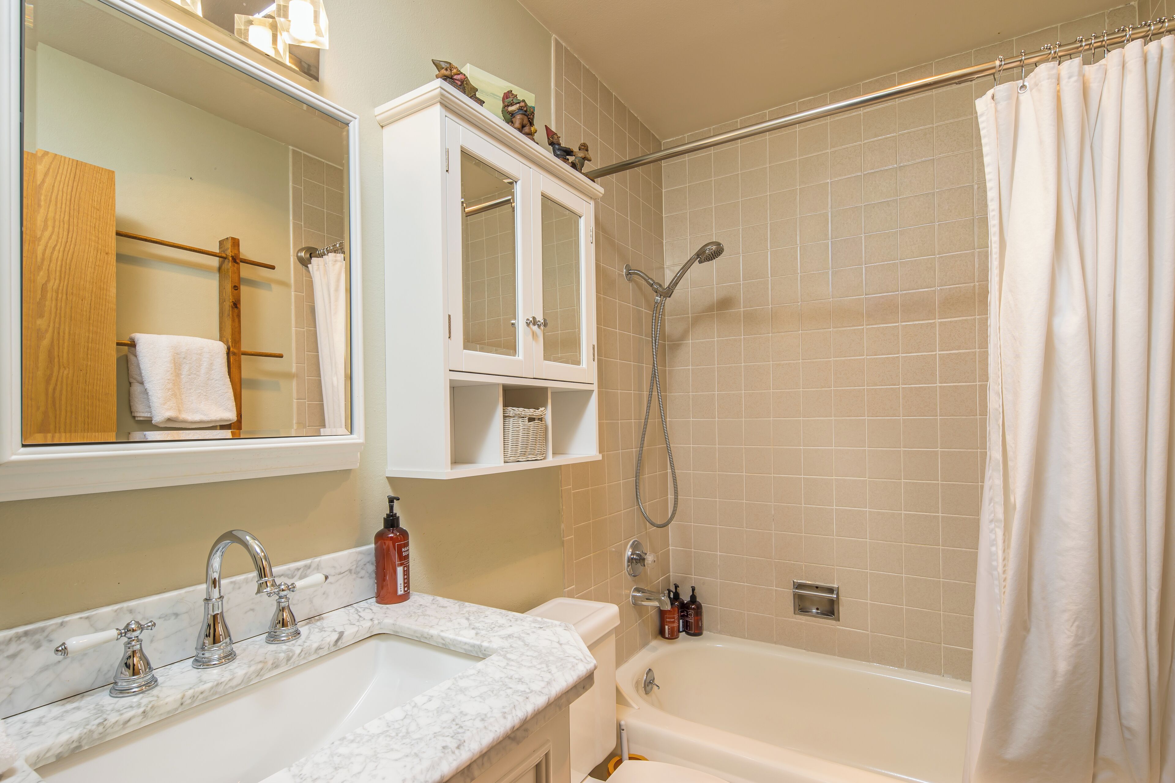 A bathroom with a white sink, a bathtub, a shower, and a mirror.