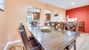 Uma área de refeições com uma mesa comprida, cadeiras de madeira e um arranjo decorativo.