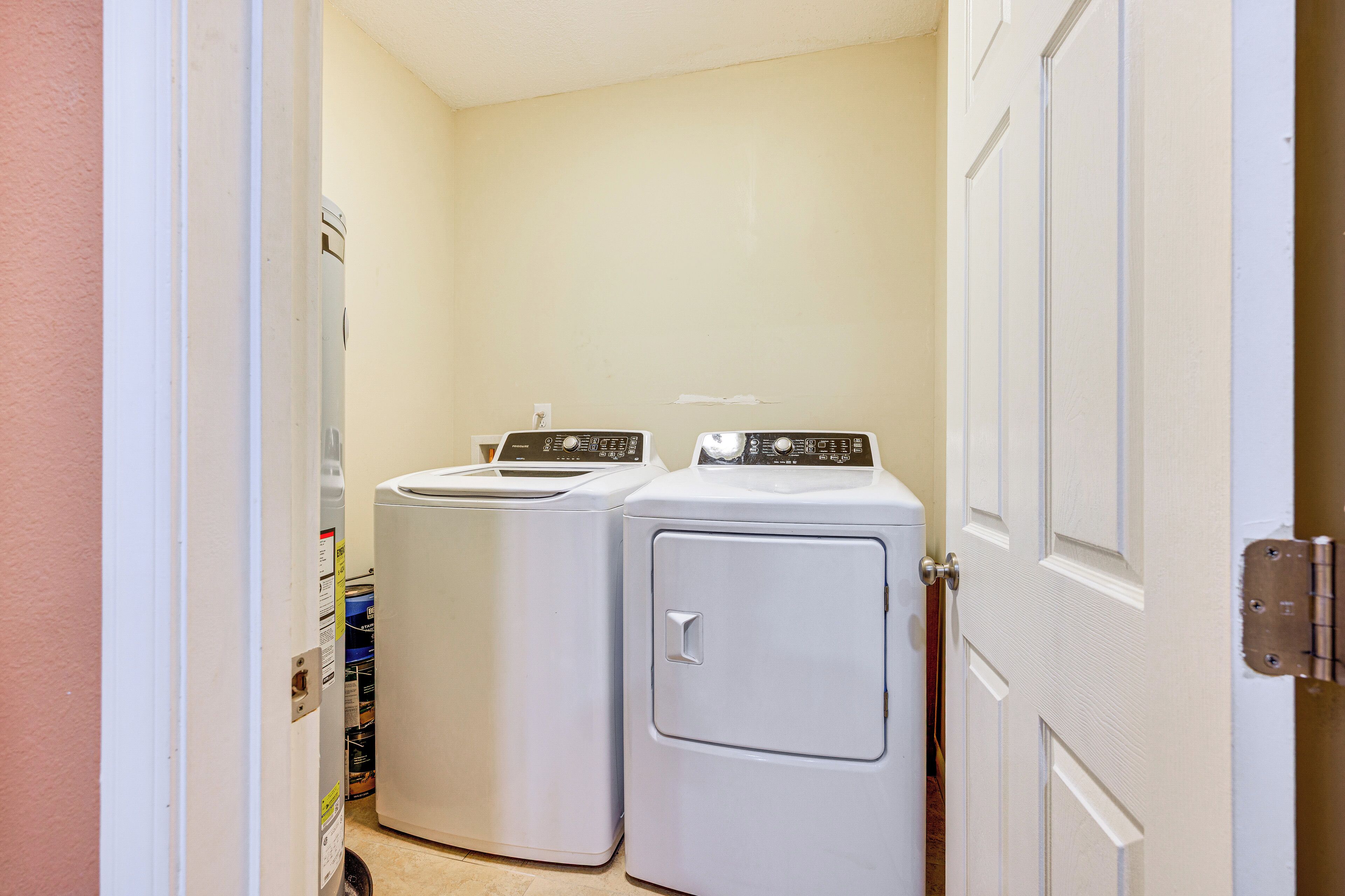 A laundry room with two stacked washers and dryers, a door, and a wall with a bulletin board.