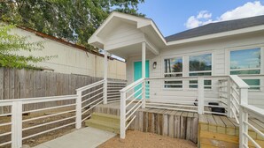 A white house with a wooden deck, a turquoise door, and a white railing. - Modern Home I Near NRG I Easy Light Rail Access (Houston)