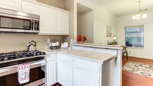 A kitchen with white cabinets, a stainless steel stove, a microwave, and a window with a view. - Explore Houston & Beyond! Spring Home w/ Backyard (Spring)