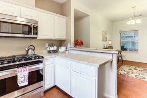 A kitchen with white cabinets, a stainless steel stove, a microwave, and a window with a view. - Explore Houston & Beyond! Spring Home w/ Backyard (Spring)