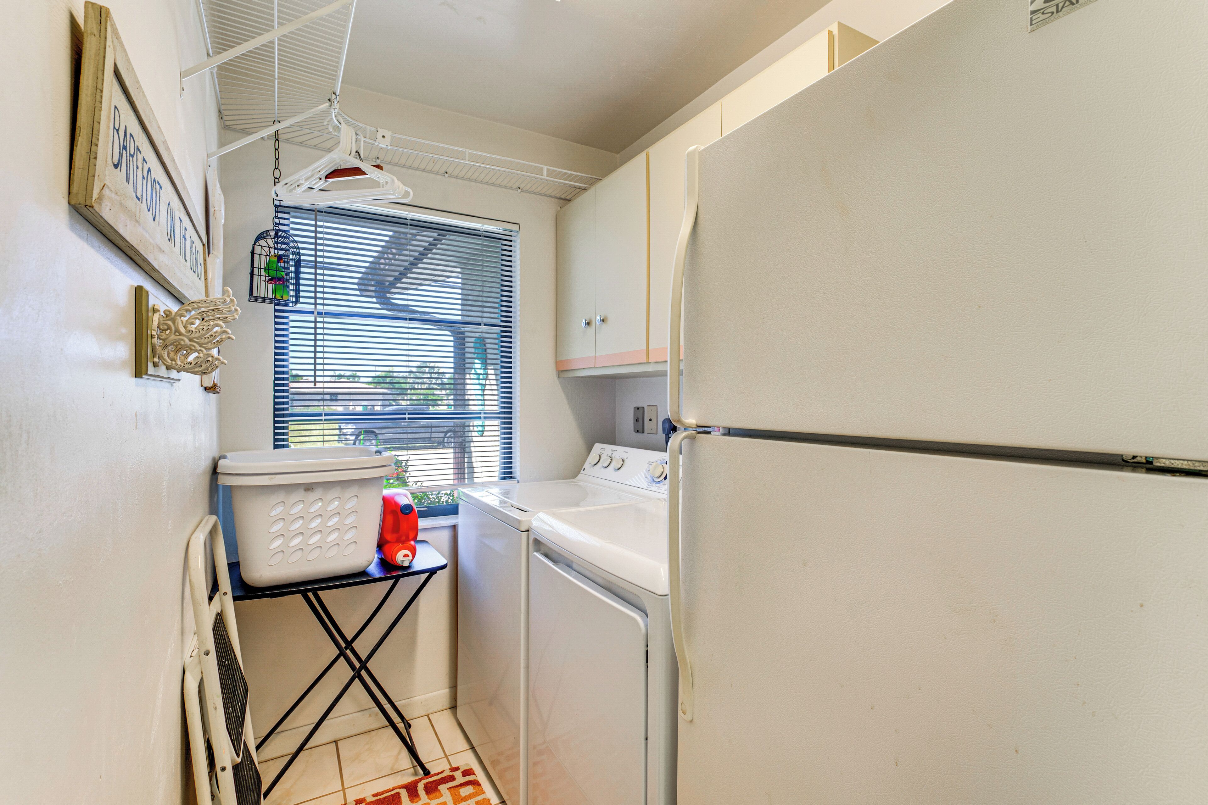 A compact laundry room with a washing machine, dryer, and a small table with a basket and detergent bottles.