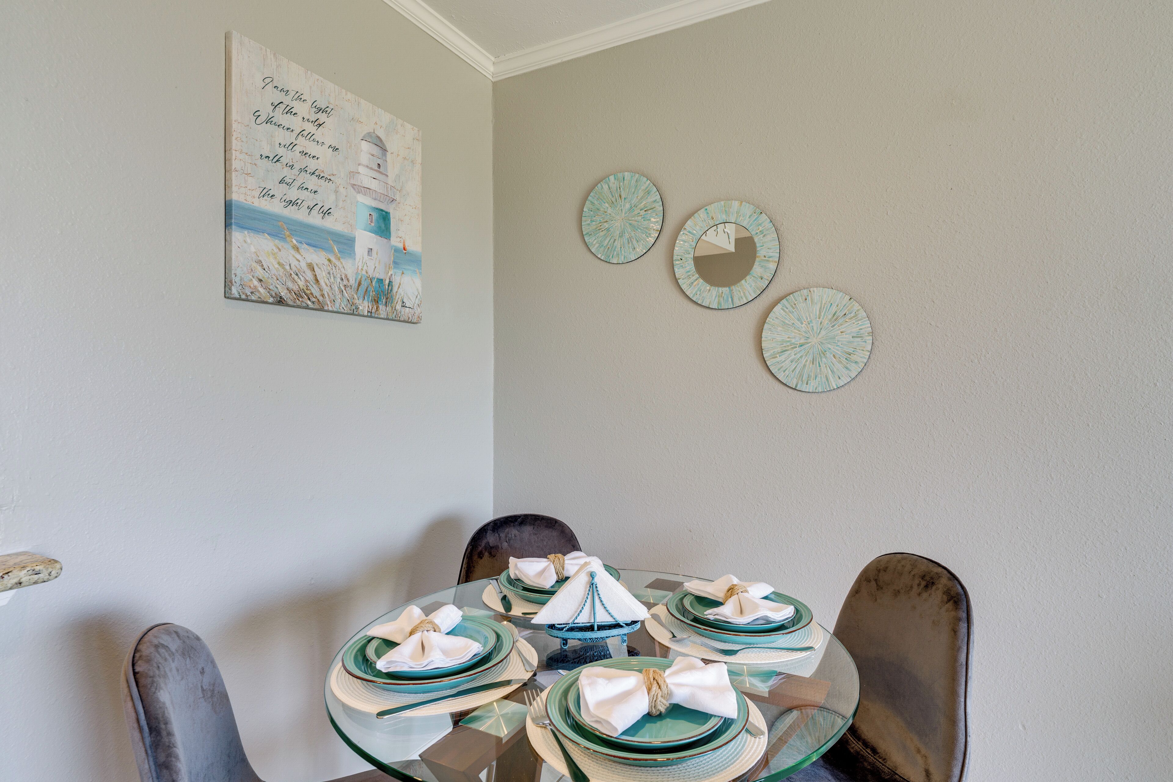 A dining area with a round glass table set for four, surrounded by chairs.