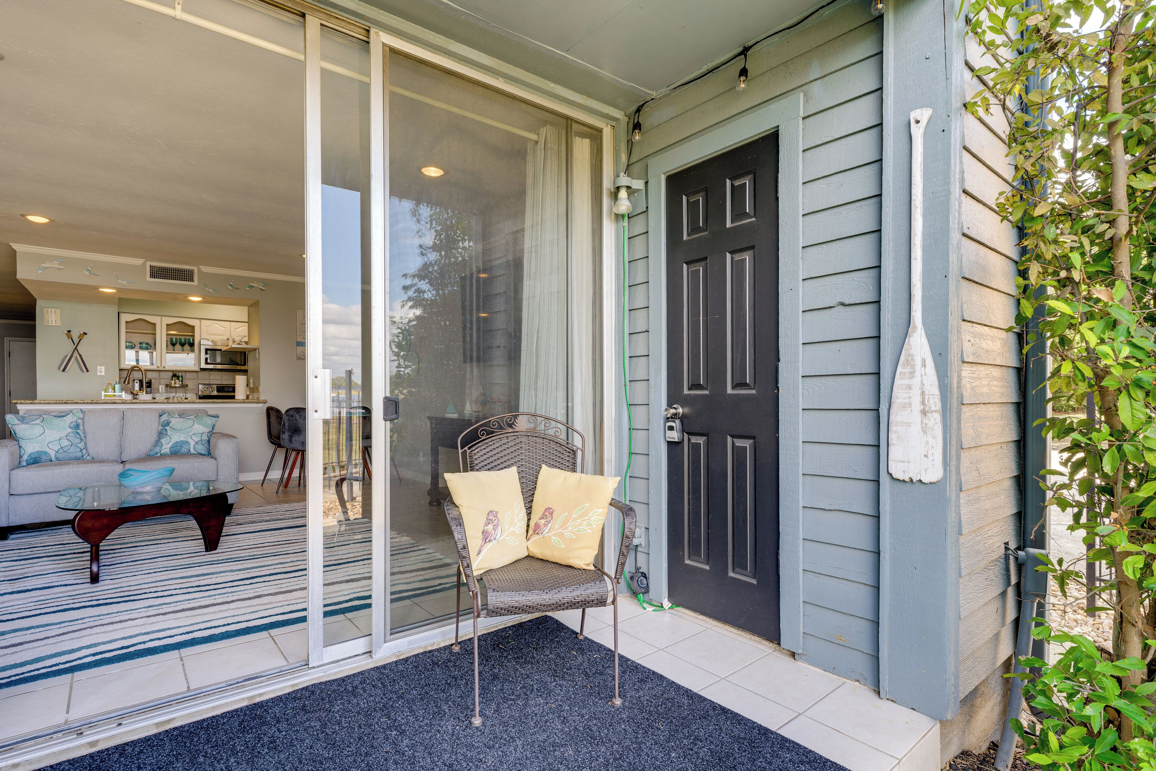 A sliding glass door leading to a living room with a sofa, a coffee table, and a chair with cushions.