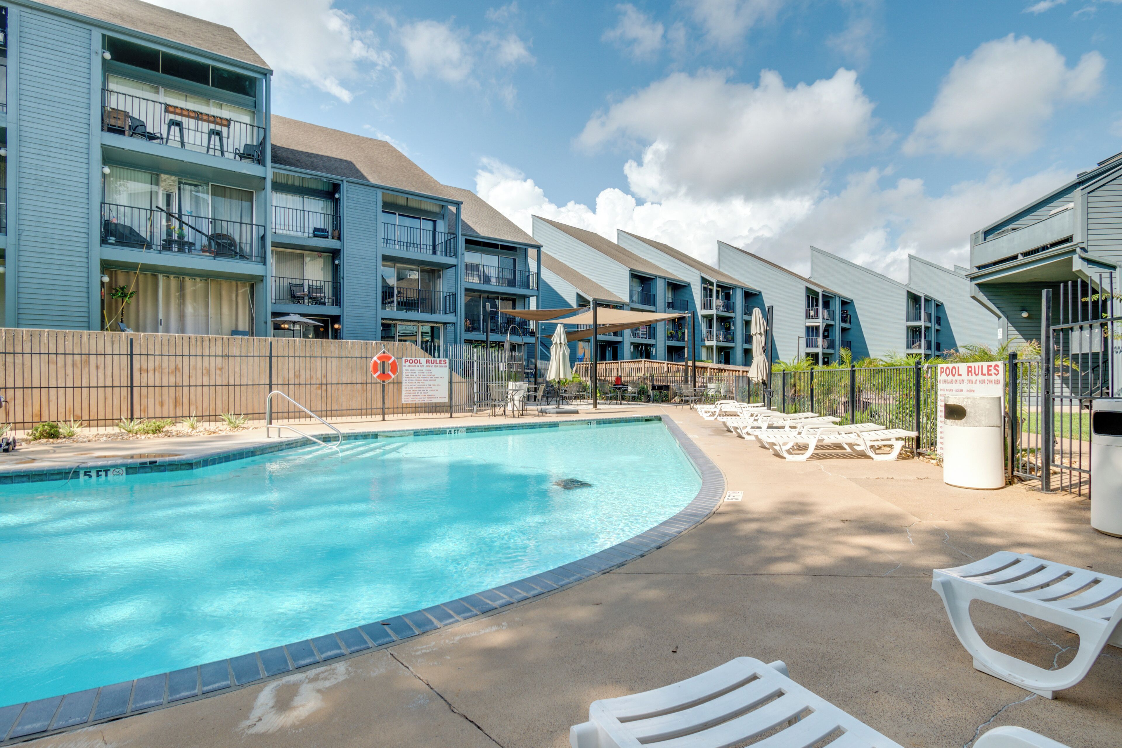 A modern hotel with a swimming pool, outdoor seating, and multiple balconies.