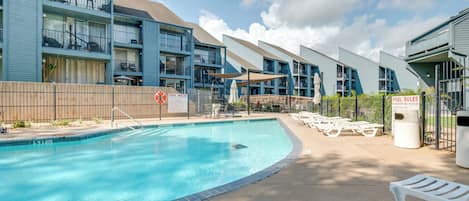 A modern hotel with a swimming pool, outdoor seating, and multiple balconies.
