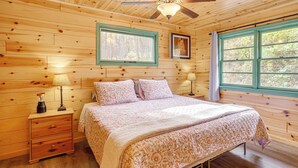 A wooden cabin bedroom with a bed, two bedside tables, a ceiling fan, and two windows. - Hike On-site! 16-acre Escape Near Shenandoah NP (Stanley)