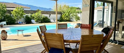 Un espace extérieur abrité, aménagé pour les repas, avec une piscine et une vue sur les montagnes.