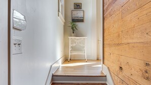 A staircase with wooden steps leading to a white wall with a small table and a plant. - Walk to Downtown Tyler! Updated Historic Apt (Tyler)