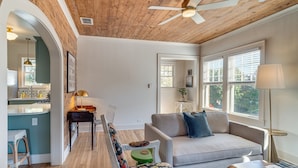 A modern living room with a sofa, a dining area with a table and chairs, and a kitchen visible through an archway. - Walk to Downtown Tyler! Updated Historic Apt (Tyler)
