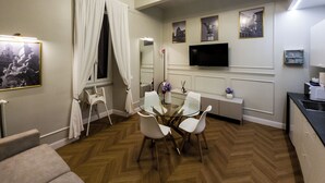 A hotel room with a dining area, a TV, and a large mirror. - Domus Innovatis Rooms & Home (Rome)