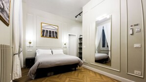 A bedroom with a bed, a large mirror, a radiator, and a picture on the wall. - Domus Innovatis Rooms & Home (Rome)