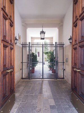A gated entrance with a tiled floor, wooden doors, and potted plants. - Domus Innovatis Rooms & Home (Rome)