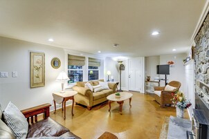 Una sala de estar con un sofá color beige, dos mesas auxiliares, una chimenea y una pared de piedra.