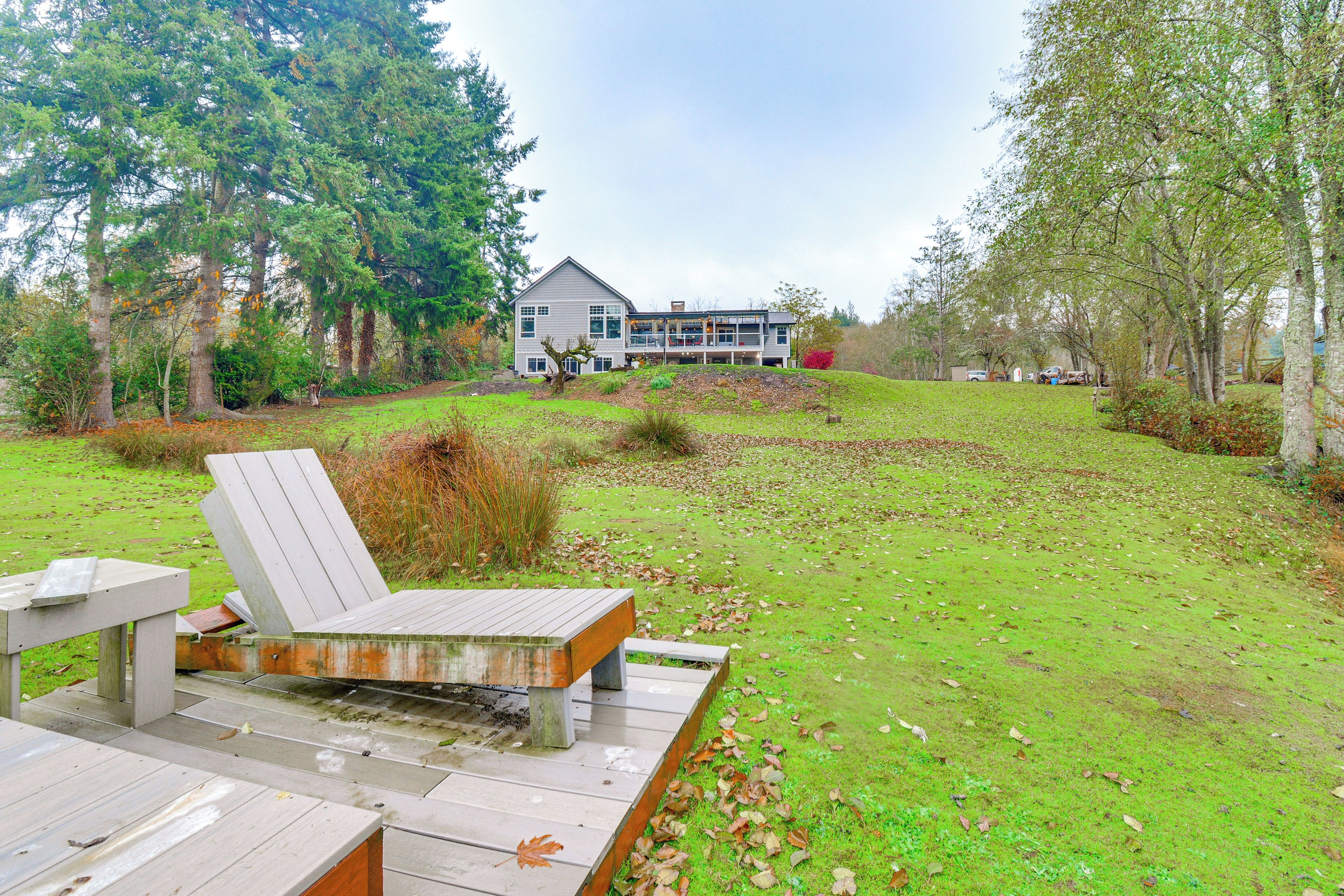 A wooden deck with a bench, a grassy area, and a house in the background.