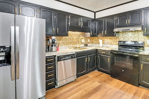 A kitchen with dark cabinets, stainless steel appliances, and a wooden floor. - 6 Mi to Marietta Square: Family Retreat w/ Yard! (Marietta)