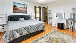 Un dormitorio con cama, televisión, escritorio y un cuadro en la pared.