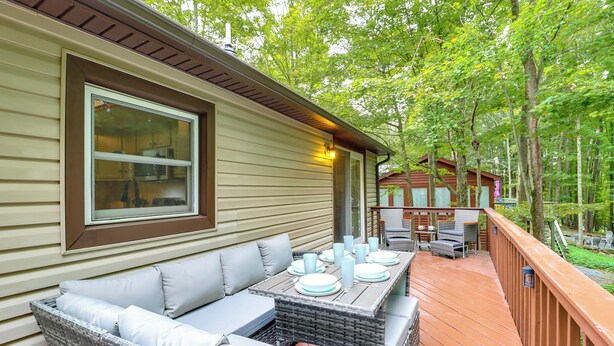 A covered outdoor dining area with a table set for four, surrounded by wicker furniture and cushions. - 1 Mi to Lake, Golf & Ski Access: The Hideout Home! (Lake Ariel)