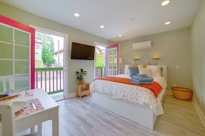 Un dormitorio con cama, una mesa, una silla, un televisor y un balcón con vistas al exterior.