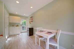 Una cocina luminosa con armarios blancos, un refrigerador y una mesa de comedor con sillas.