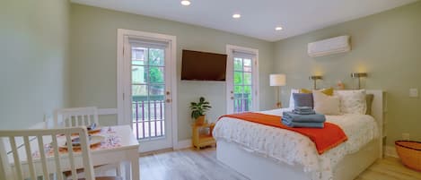 A bedroom with a bed, bedside tables, a TV, and a window.