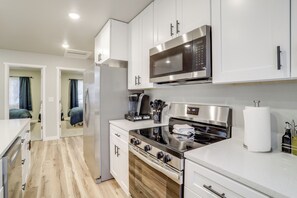 A modern kitchen with stainless steel appliances, wooden flooring, and white cabinetry. - Modern & Pet-friendly! Northern Colorado Retreat (Severance)