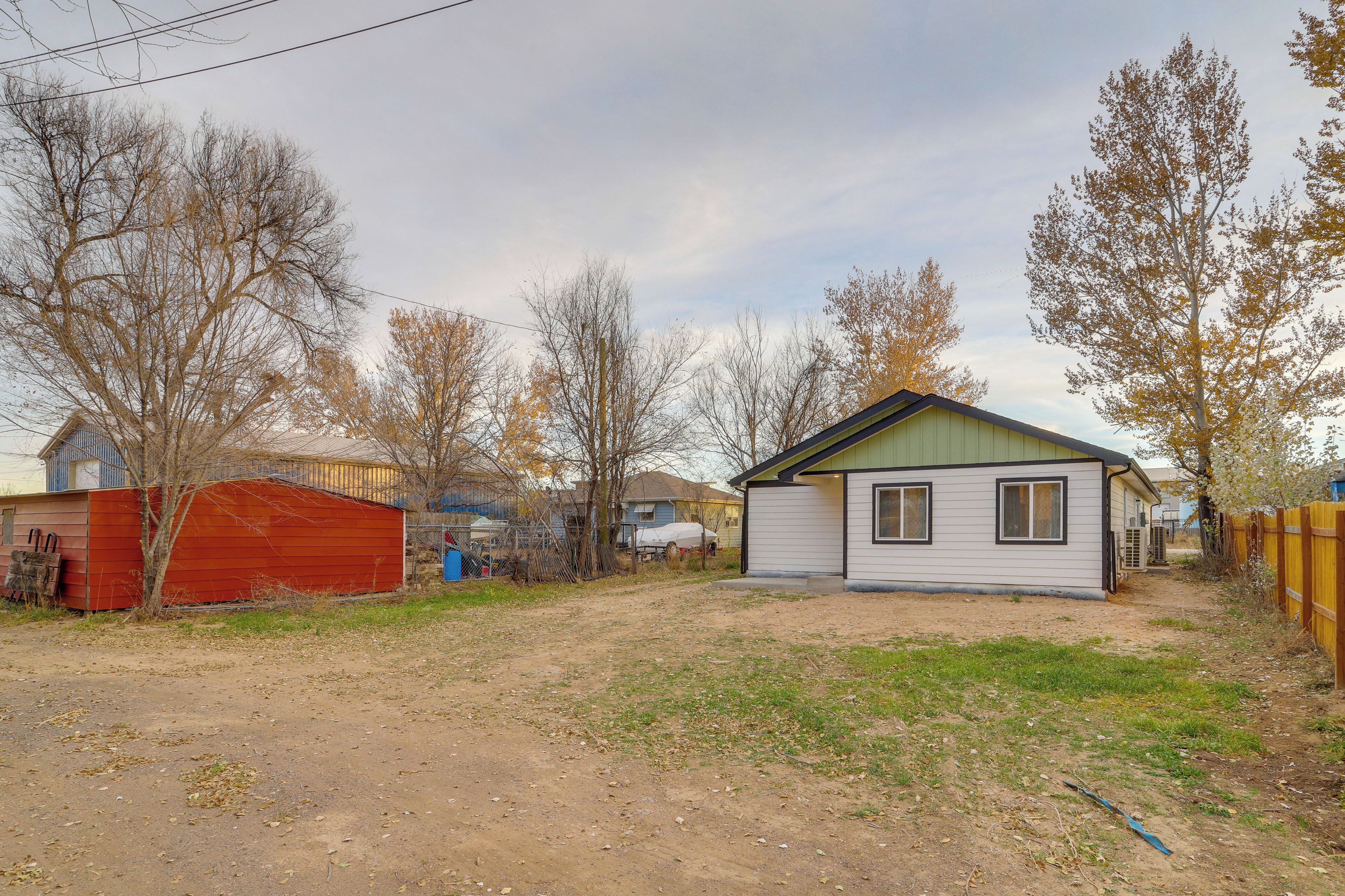 A residential area with a small house, a red shed, and a fenced yard.