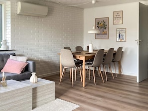 Ein modernes Wohnzimmer mit Essbereich, mit Backsteinwand, Sofa, Couchtisch und Esstisch mit Stühlen.
