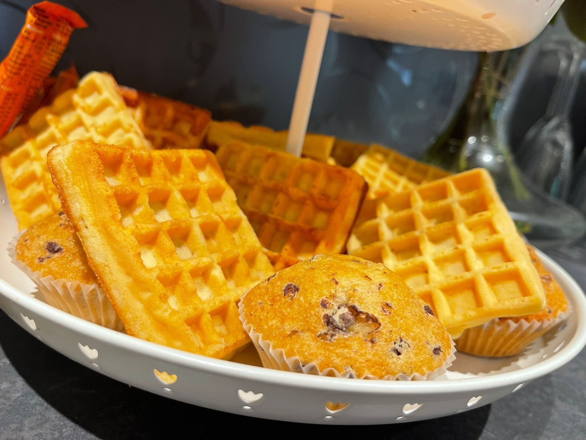 Un bol blanc amb guaïlles i un muffin, damunt d'una superfície fosca.
