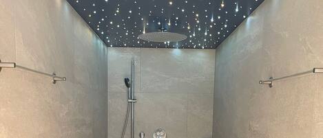 A modern shower with a handheld showerhead and a wall-mounted control panel.